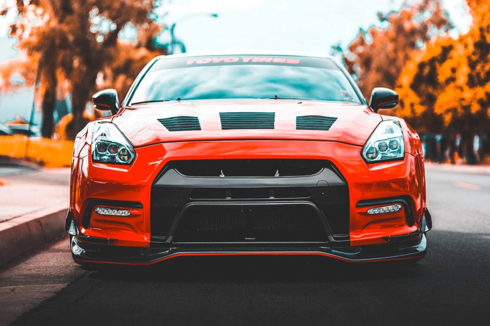 A red car with black stripes on the hood.