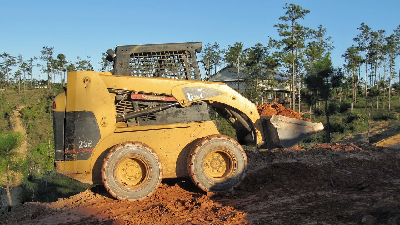 A yellow and black skid steer is on the dirt
